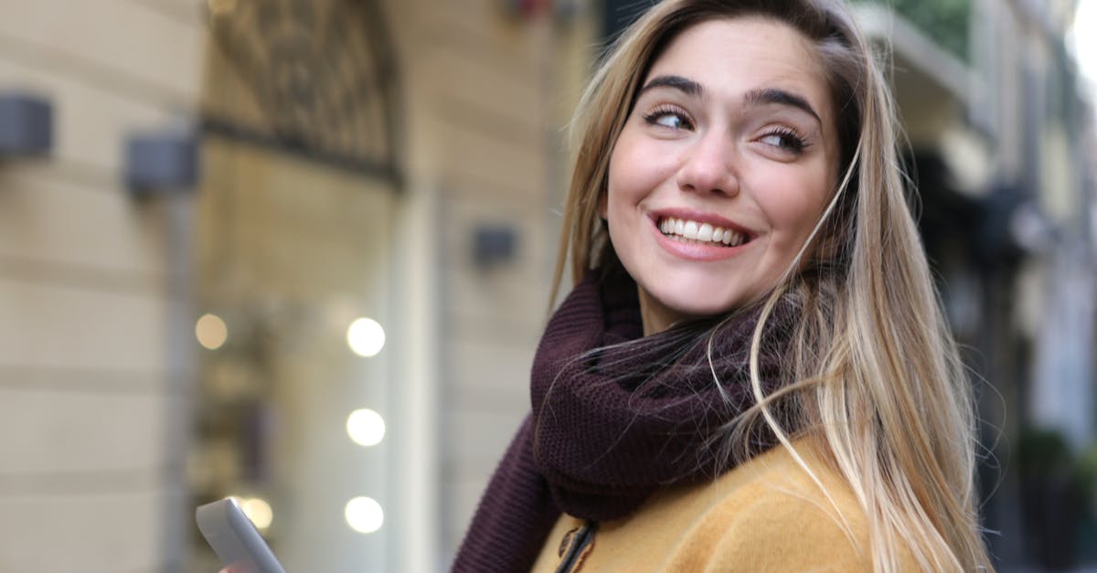 Happy young woman with blonde hair and smartphone enjoying a day outdoors.